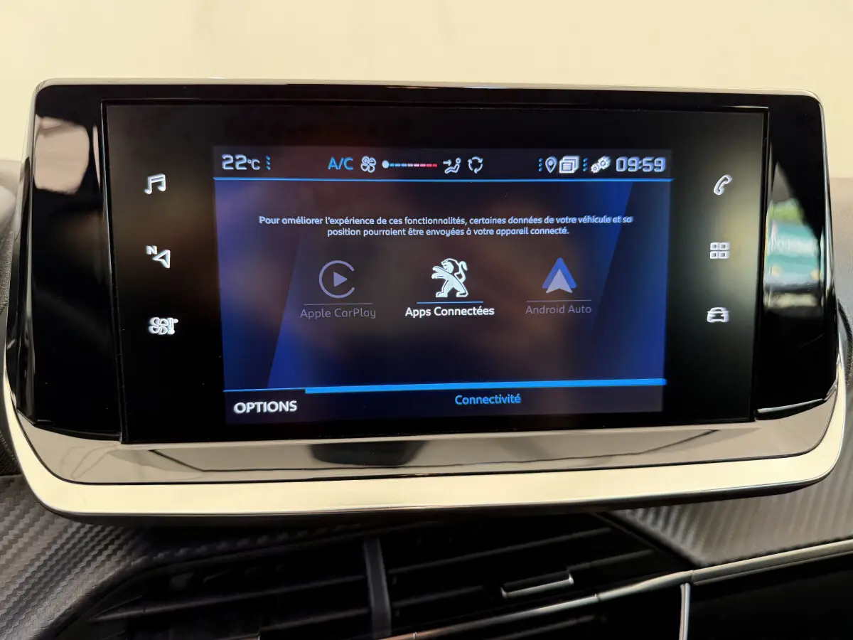 Écran tactile central affichant Apple CarPlay et Android Auto dans le tableau de bord noir d'une Peugeot 208 2021.