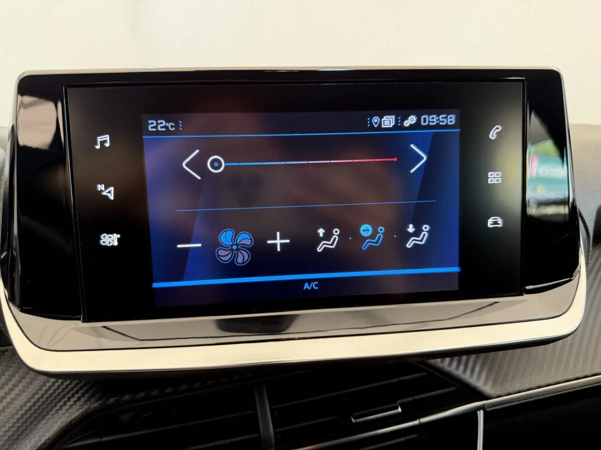 Écran tactile central de la climatisation sur tableau de bord d'une Peugeot 208 noire, vue rapprochée.
