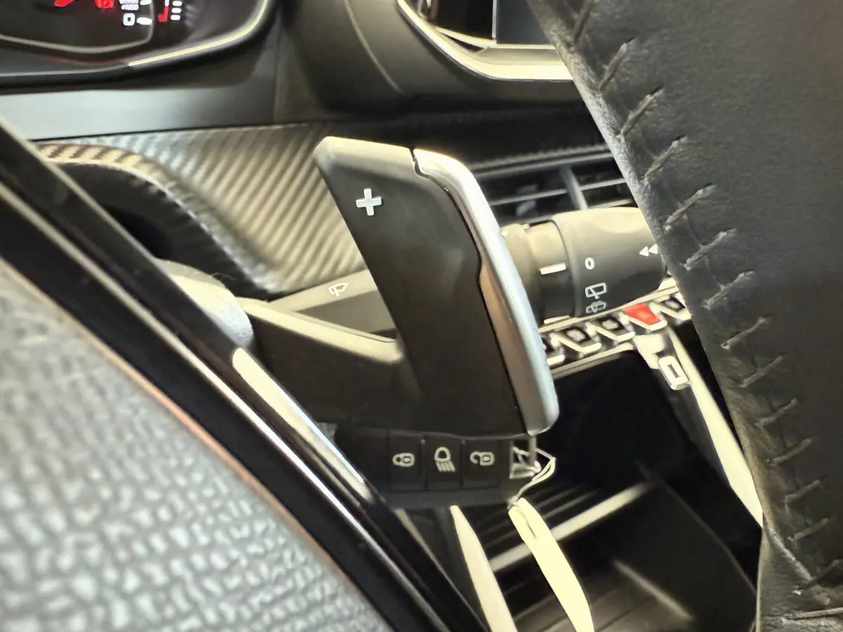 Gros plan sur la palette de changement de vitesse droite et le volant cuir noir de la Peugeot 208 PureTech 100.
