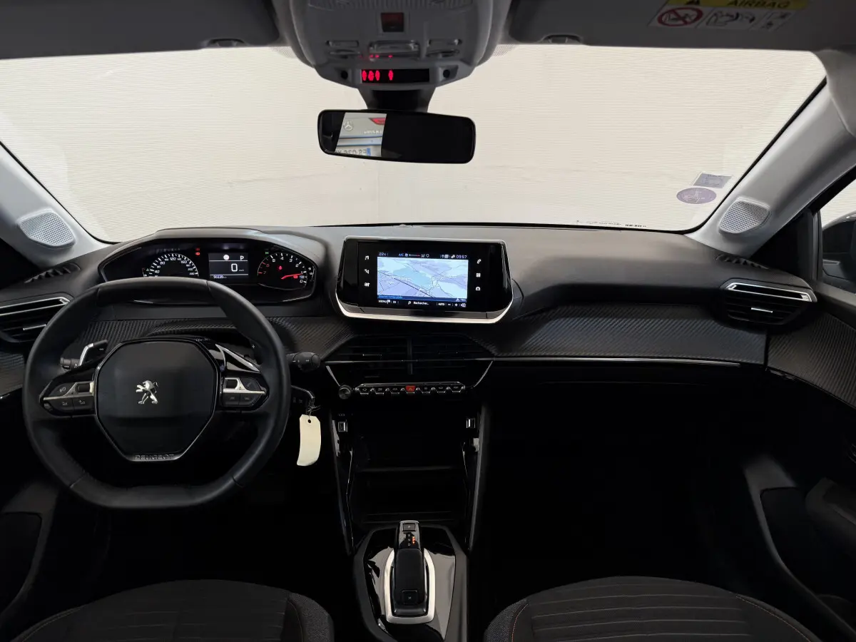 Intérieur noir de la Peugeot 208 PureTech 2021 vu de face, avec tableau de bord numérique et écran tactile central.
