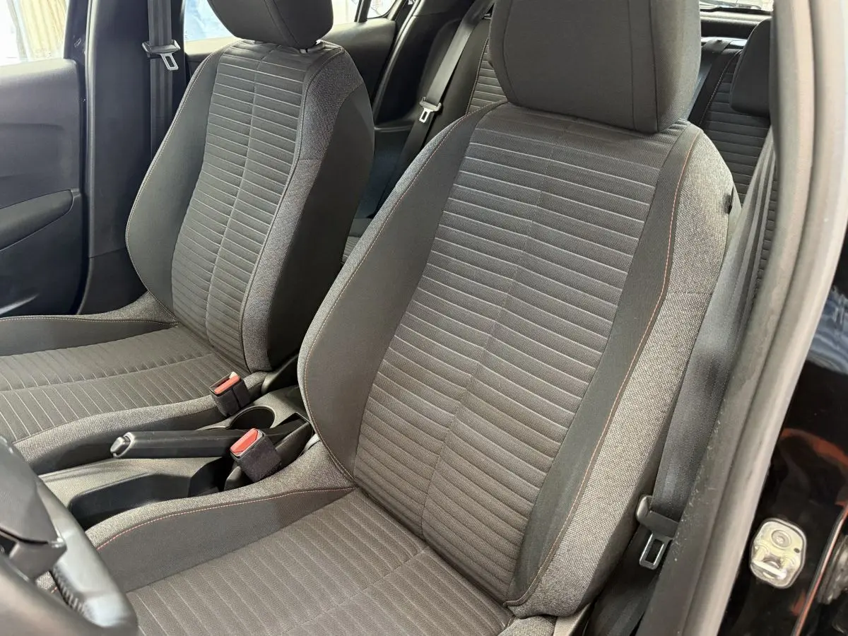 Gros plan sur les sièges avant gris foncé de la Peugeot 208 PureTech 100 Active Business, côté conducteur ouvert.