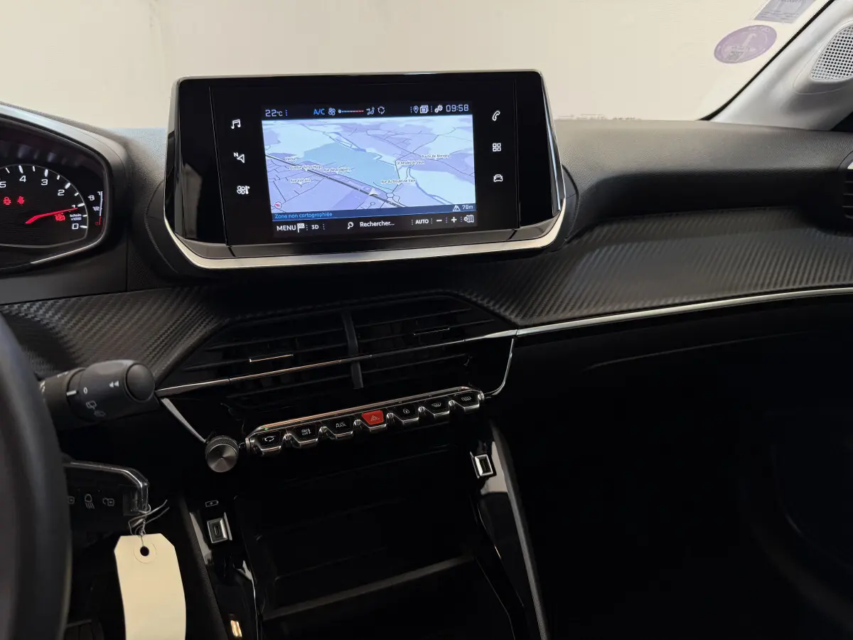 Vue intérieure du tableau de bord de la Peugeot 208 noire, avec écran tactile de navigation et finition carbone.