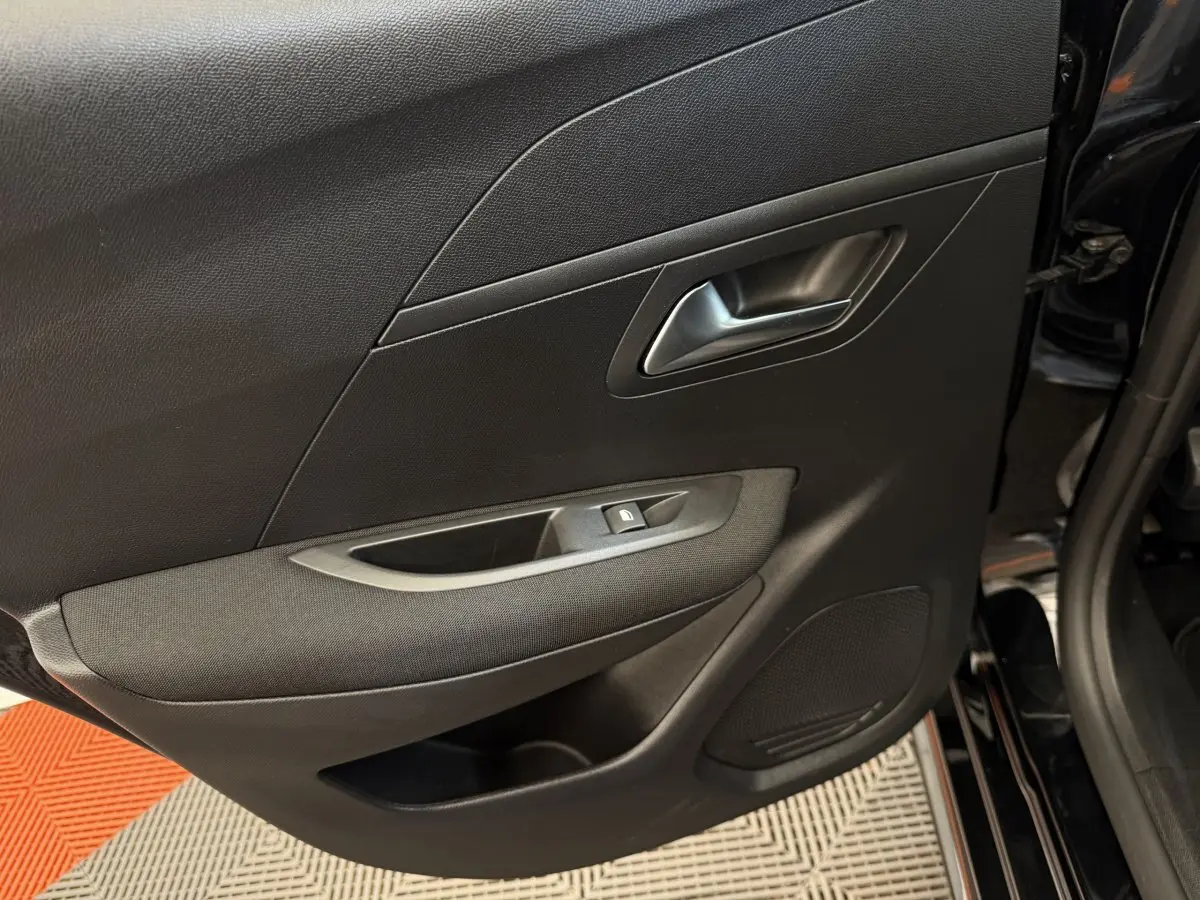 Gros plan sur la porte côté gauche noire de la Peugeot 208 2021, avec poignée argentée et commande de lève-vitre.