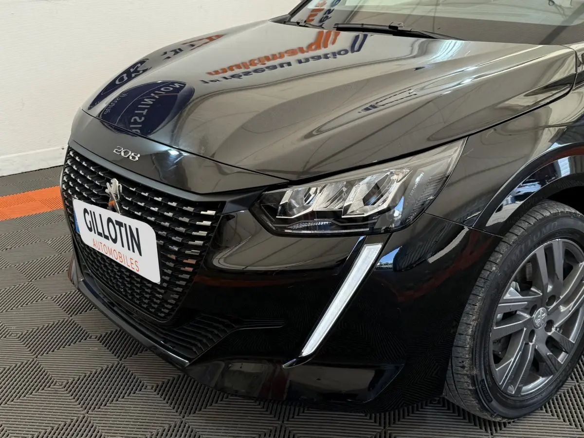 Vue 3/4 avant droit d'une Peugeot 208 noire mettant en valeur sa calandre distinctive et ses phares LED effilés.
