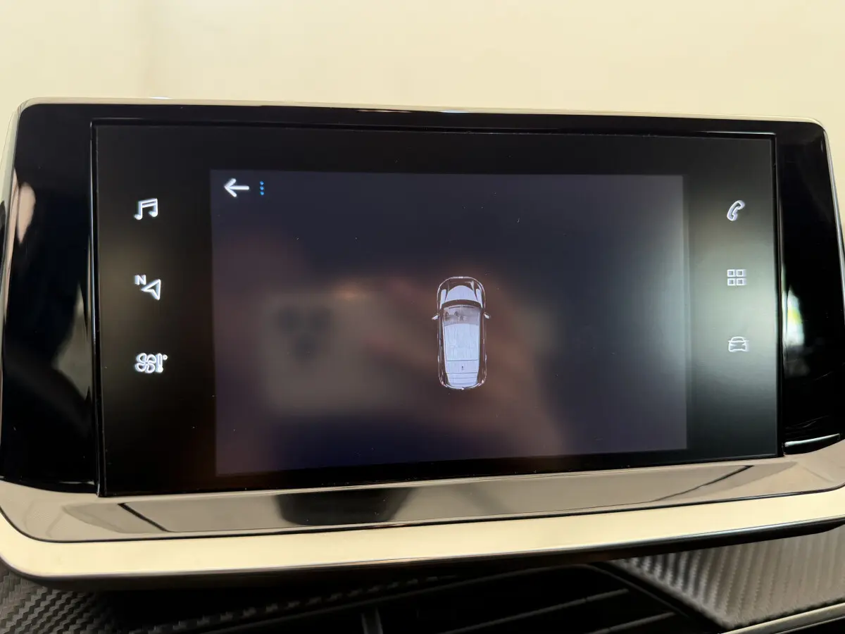 Écran tactile central affichant la vue aérienne du véhicule Peugeot 208 noir, tableau de bord moderne.