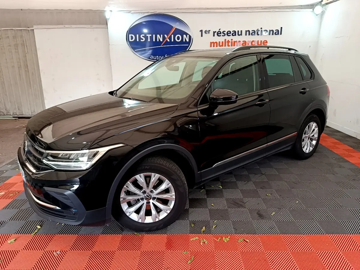 Volkswagen Tiguan noir vu en 3/4 avant droit dans un showroom avec jantes argentées et toit noir.