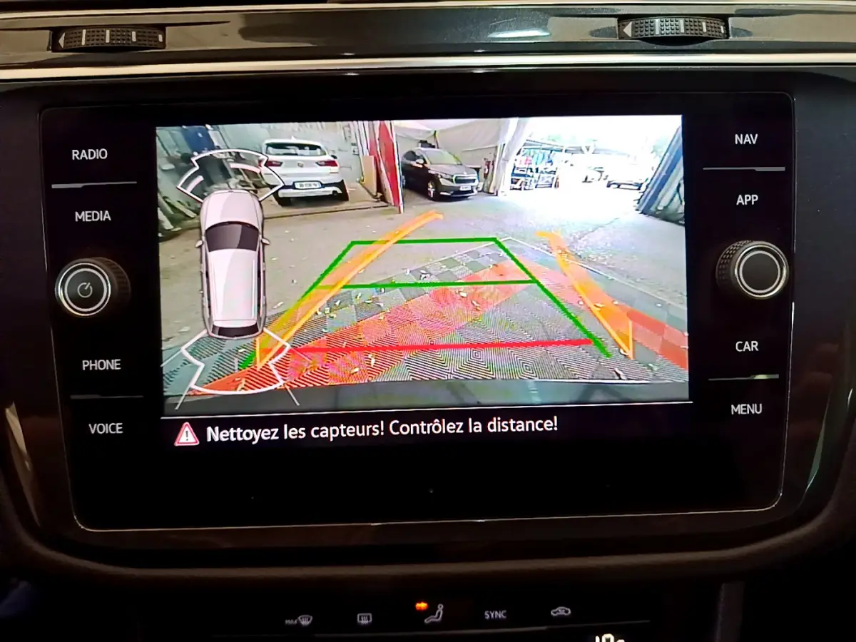 Écran tactile intérieur du Volkswagen Tiguan noir montrant la caméra de recul avec guidage de trajectoire coloré.