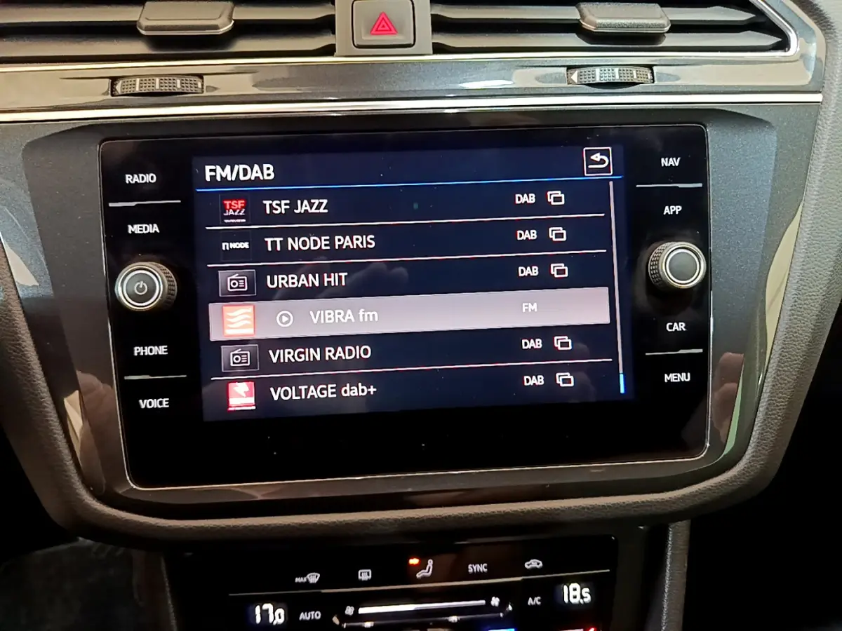 Écran tactile central du Volkswagen Tiguan noir 2021 affichant les stations radio FM/DAB dans l'habitacle.
