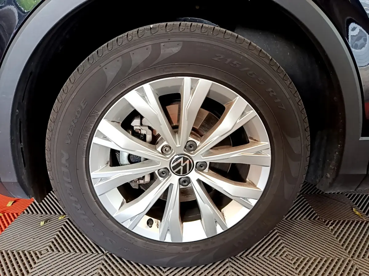 Gros plan sur la roue avant droite d’un Volkswagen Tiguan noir, mettant en valeur la jante argentée à 10 branches.
