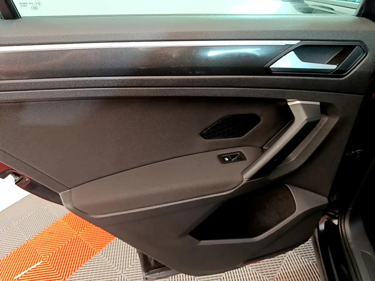 Vue intérieure de la porte arrière droite noire du Volkswagen Tiguan 2021 avec poignée argentée et commande de vitre électrique.