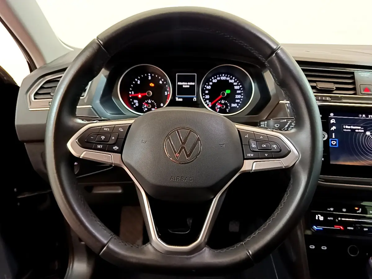 Vue rapprochée du volant cuir noir du Volkswagen Tiguan 2021 avec tableau de bord et écran tactile visibles.