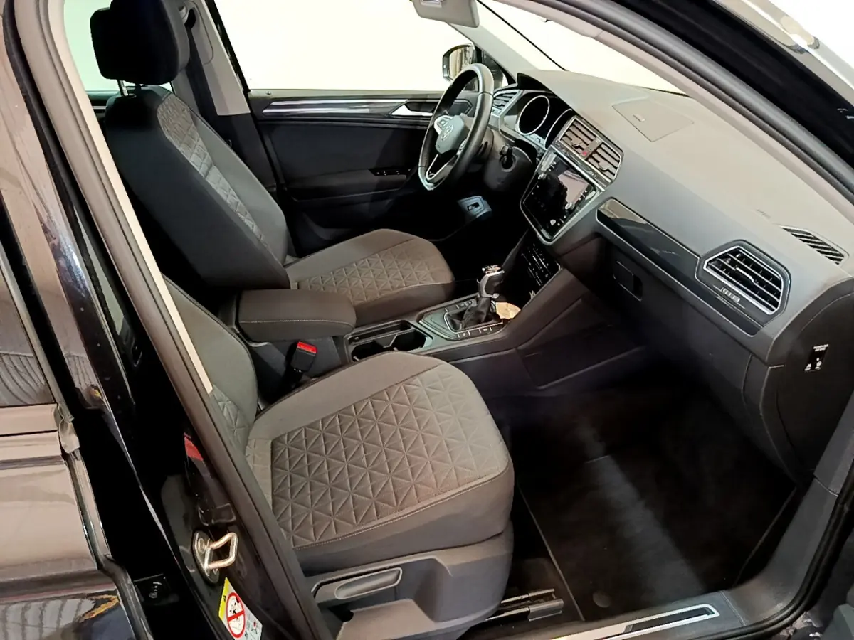 Intérieur avant côté conducteur du Volkswagen Tiguan noir 2021, sièges tissu gris à motifs géométriques et tableau de bord moderne.