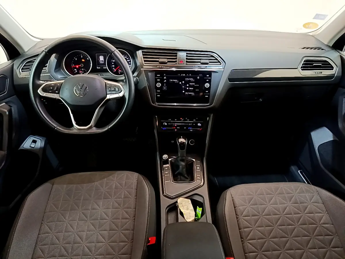 Intérieur du Volkswagen Tiguan 2.0 TDI 2021 vu de face, tableau de bord noir avec écran tactile central et volant cuir.