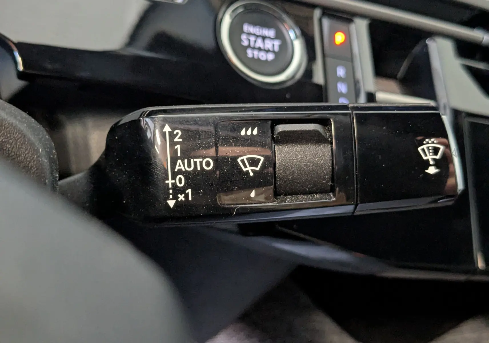 Gros plan sur la commande des essuie-glaces du Peugeot 3008 Hybrid blanc, avec bouton start/stop en arrière-plan.