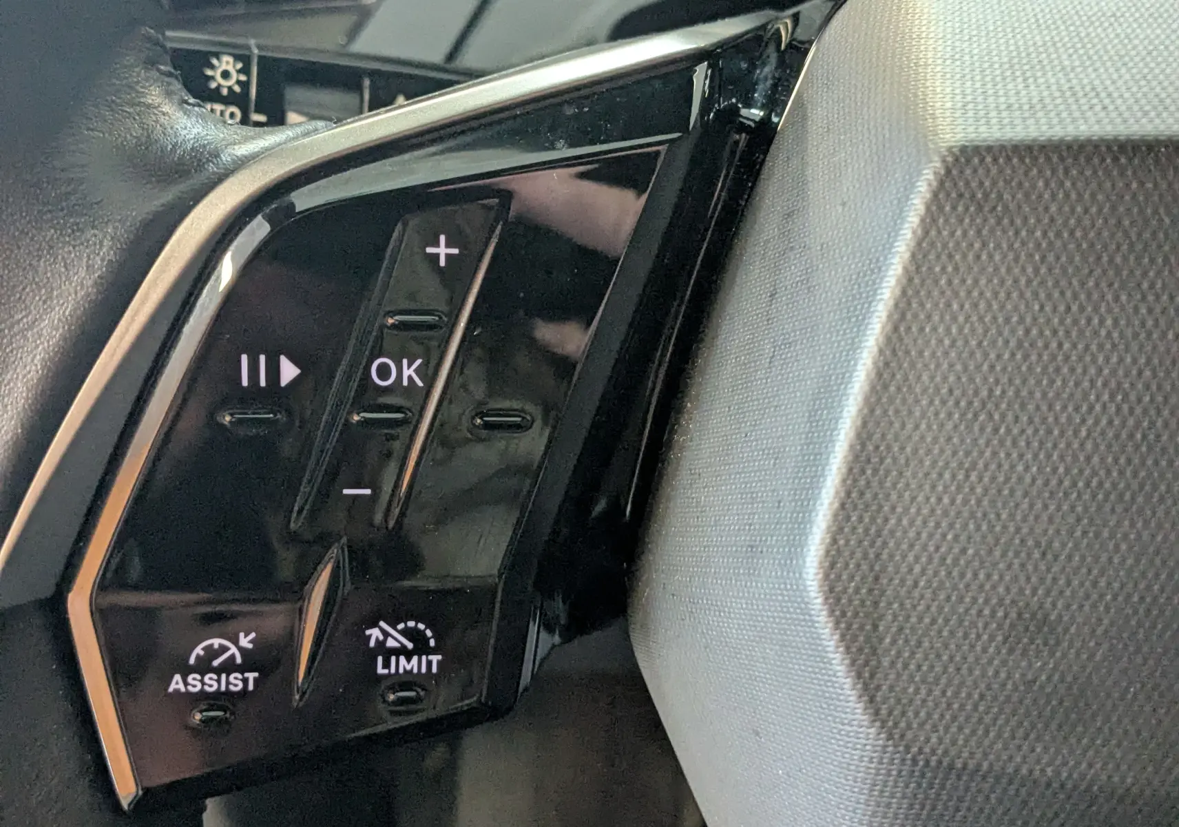 Gros plan sur les commandes de régulateur et limiteur de vitesse au volant d’un Peugeot 3008 Hybrid blanc.