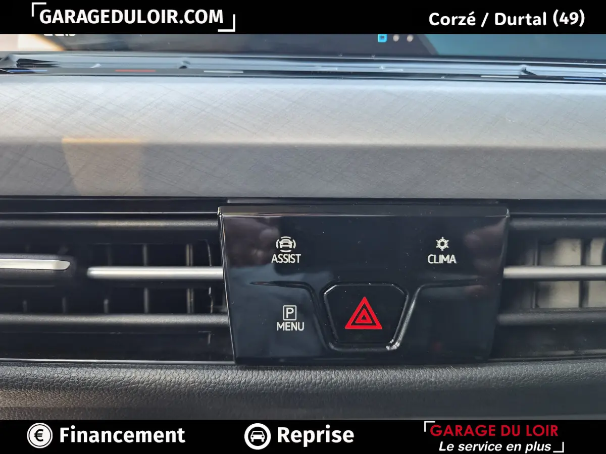 Gros plan sur la console centrale noire avec boutons d'assistance, climatisation et alerte de danger de la Volkswagen Golf bleue 2023.