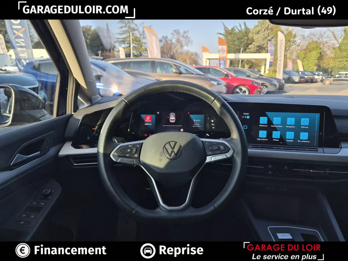 Vue intérieure centrée sur le volant cuir noir et le tableau de bord numérique de la Volkswagen Golf bleue 2023.