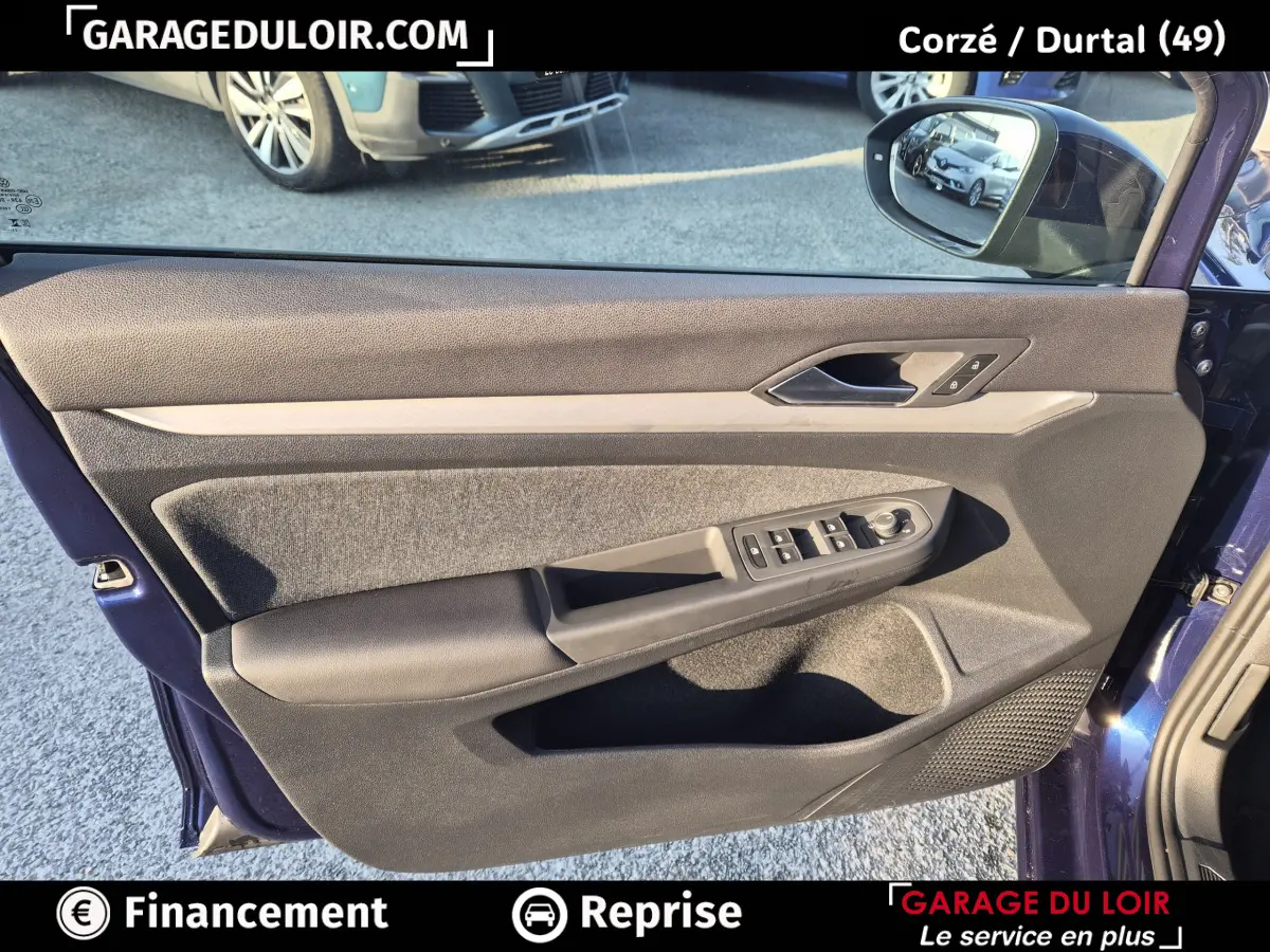 Vue intérieure de la porte avant gauche bleu foncé de la Volkswagen Golf 2023 avec commandes électriques et garniture tissu et cuir.