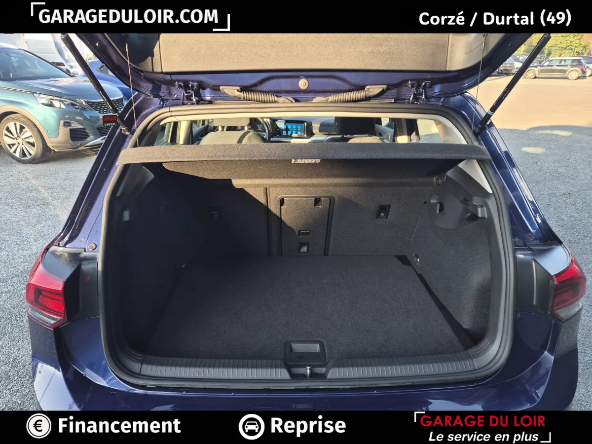 Vue arrière ouverte sur le coffre spacieux d'une Volkswagen Golf 2023 bleu, avec tablette cache-bagages relevée.