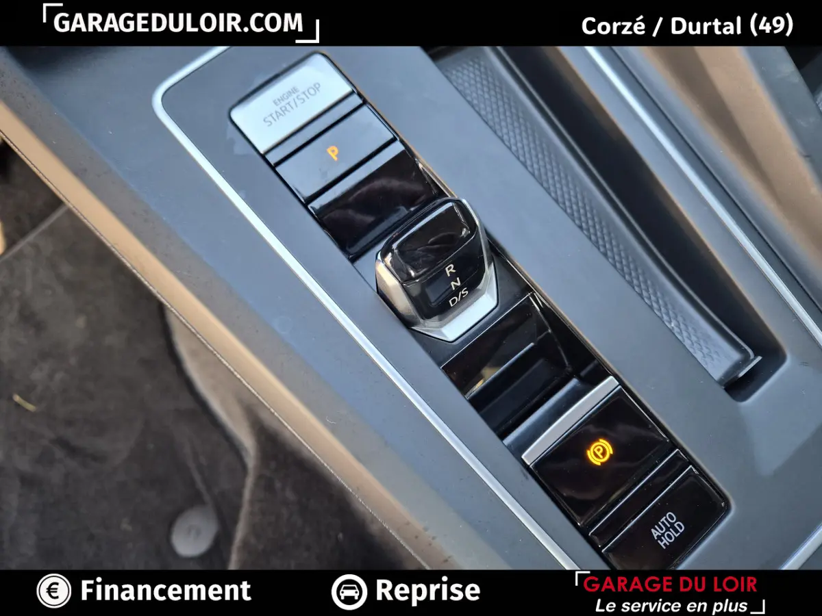 Gros plan sur la console centrale de la Volkswagen Golf 2023, montrant le levier de vitesses automatique et le bouton de frein à main électronique.