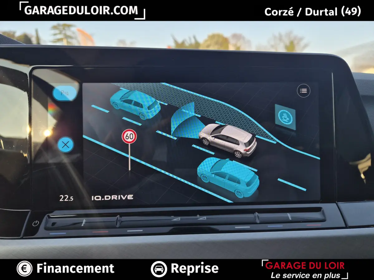 Affichage tactile intérieur de la Volkswagen Golf 2023 montrant l'assistance au maintien de voie et la détection des véhicules alentours.