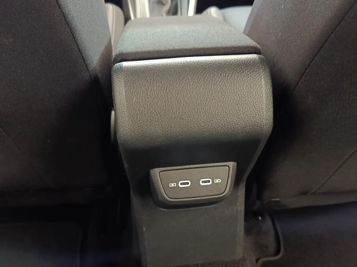 Vue rapprochée de la console centrale arrière noire avec deux ports USB-C entre les sièges avant noirs.