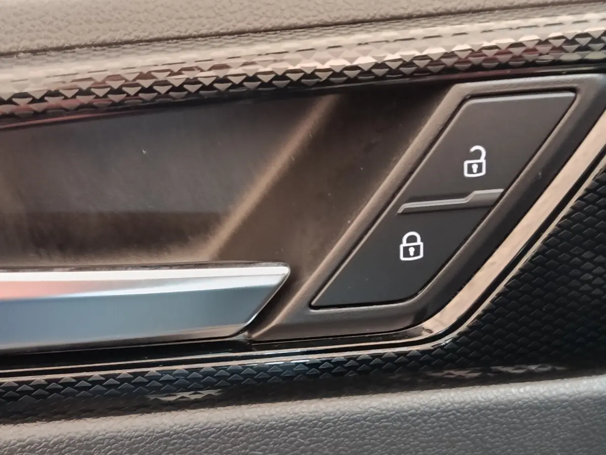 Gros plan sur la poignée intérieure et les boutons de verrouillage de porte du Volkswagen Taigo gris foncé 2023.