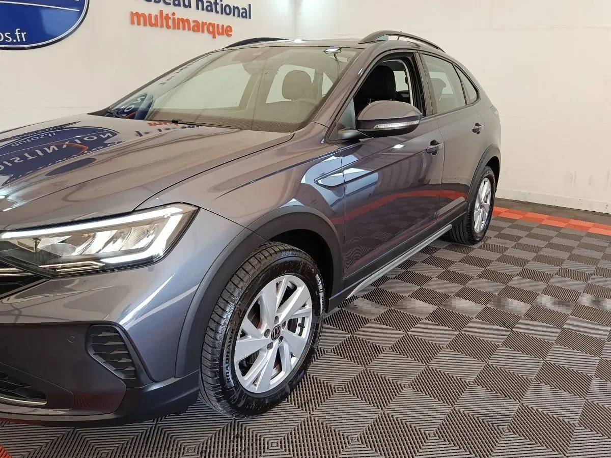 Vue 3/4 avant droit d’un Volkswagen Taigo gris foncé, mettant en valeur ses phares LED et jantes alliage.