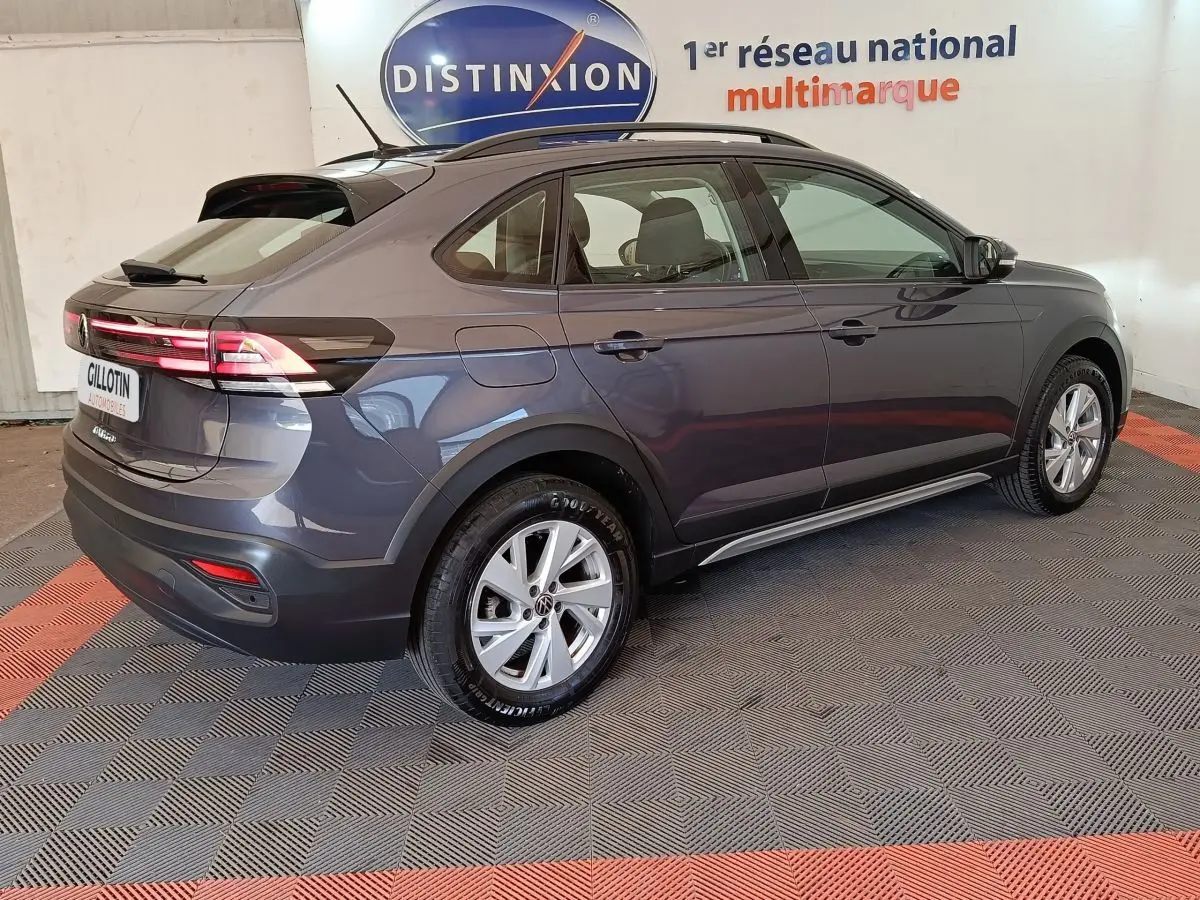 Vue 3/4 arrière droit d’un Volkswagen Taigo gris foncé 2023 avec feux arrière allumés et jantes alliage.