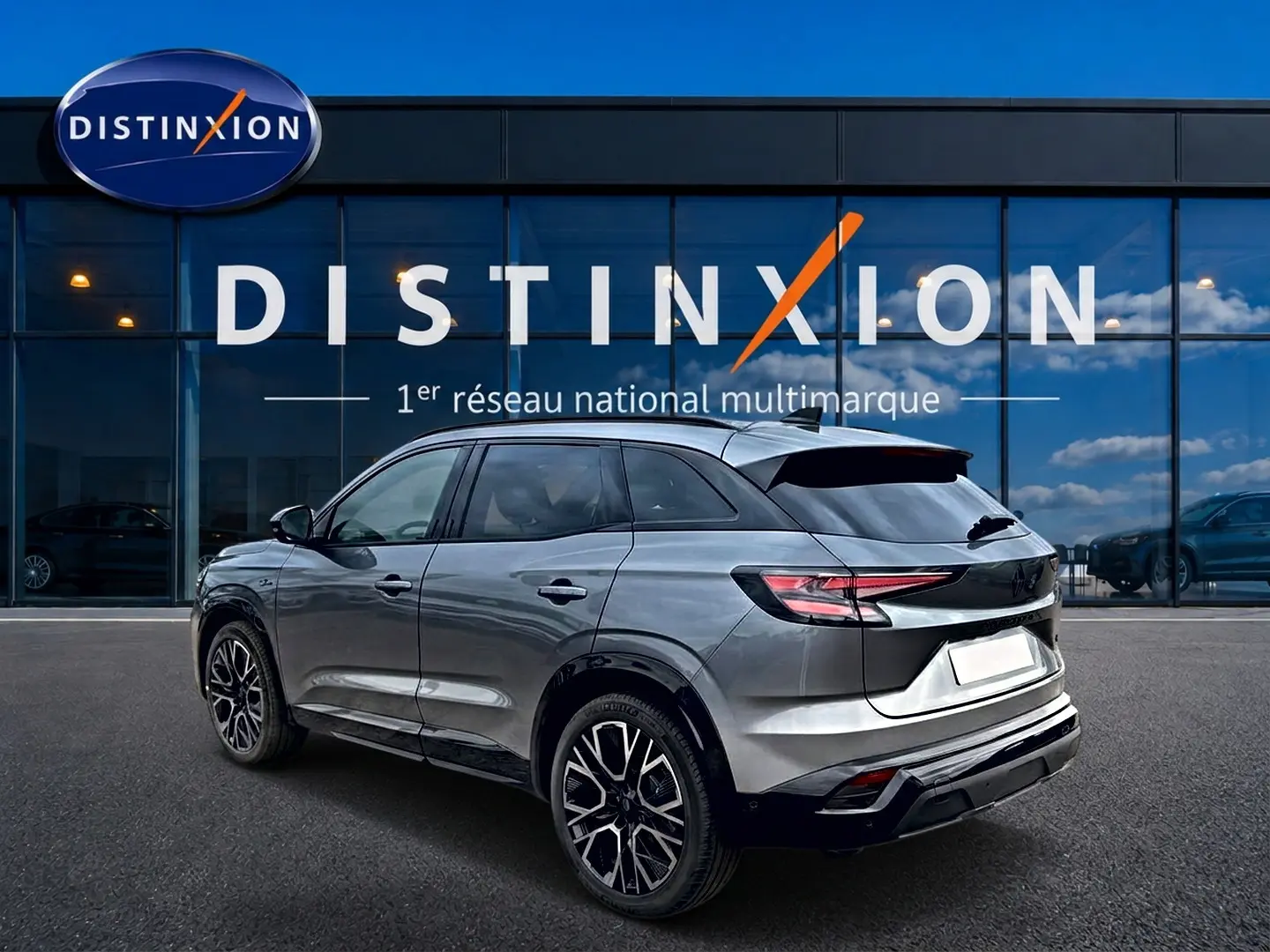 Renault Austral gris schiste en 3/4 arrière droit, avec jantes alu noires et toit noir brillant devant vitrine Distinxion.