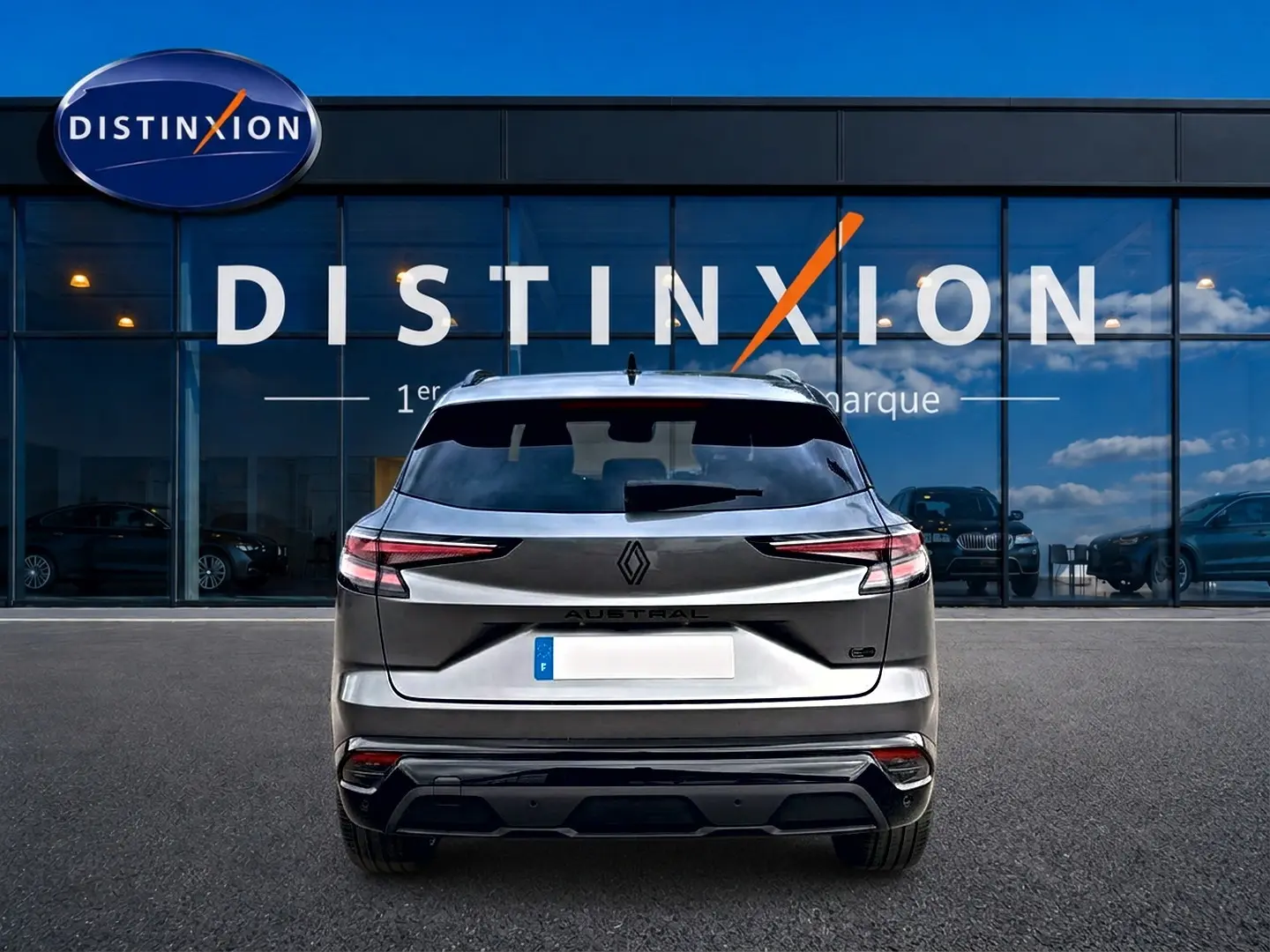 Vue arrière d'un Renault Austral gris schiste garé devant une vitrine avec logo Distinxion en arrière-plan.
