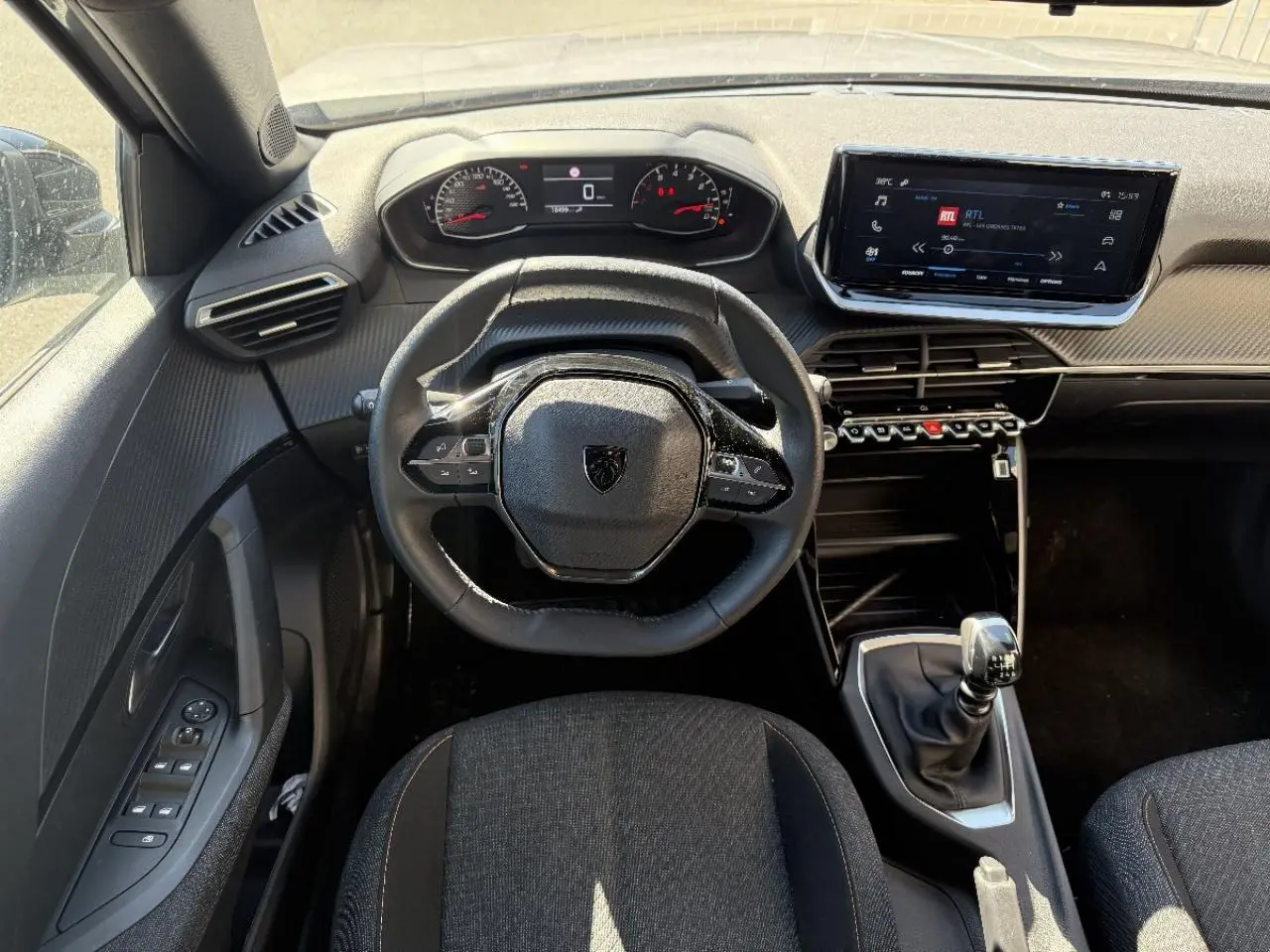 Vue intérieure avant du Peugeot 2008 2025 essence artense, volant compact, tableau de bord numérique et boîte manuelle.