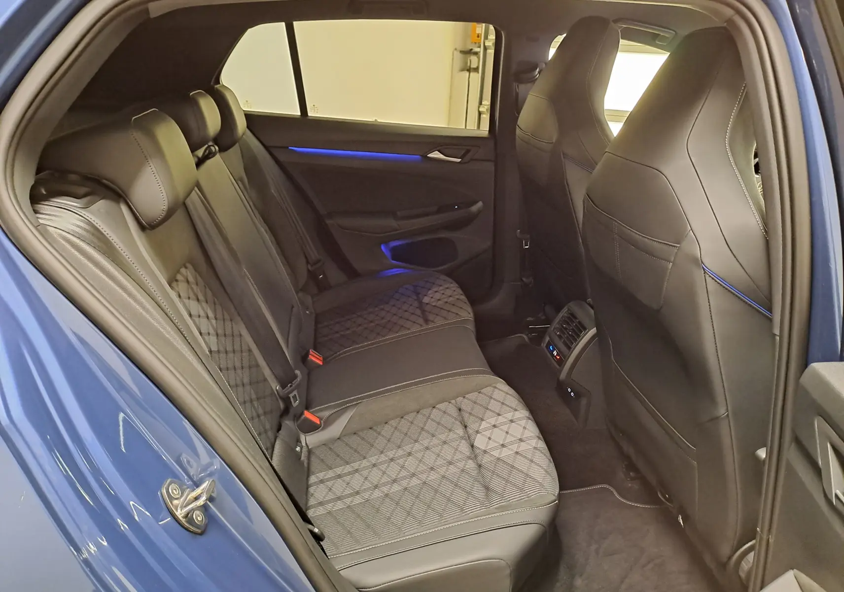 Vue intérieure côté gauche des sièges arrière en tissu et cuir avec surpiqûres bleues du Volkswagen Golf Bleu Anémone 2025 R-Line Edition.
