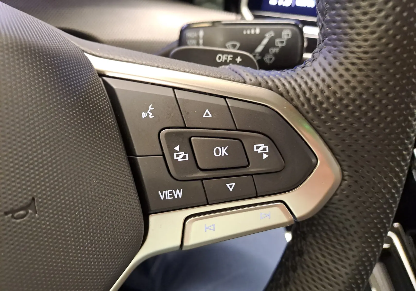 Gros plan sur les commandes multifonctions au volant perforé d'une Volkswagen Golf 1.5 eTSI Bleu Anémone, version R-Line.