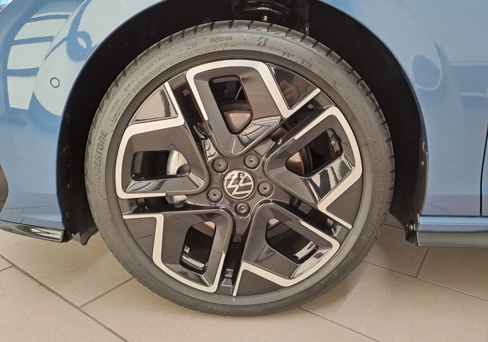 Gros plan sur la roue avant droite de la Volkswagen Golf Bleu Anémone avec jante alliage R-Line au design moderne.