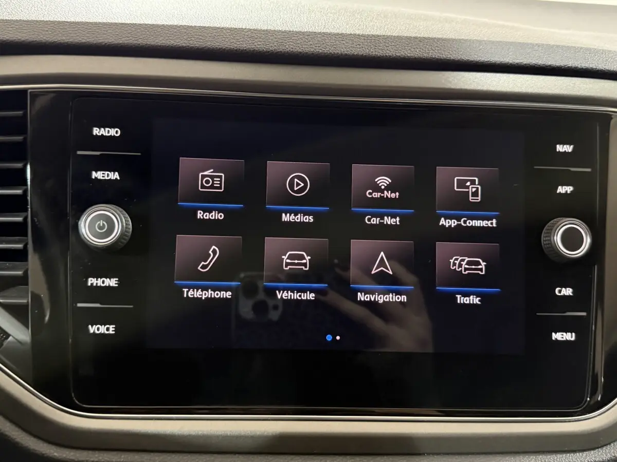 Écran tactile central du tableau de bord du Volkswagen T-Roc blanc, affichant les options multimédia et navigation.