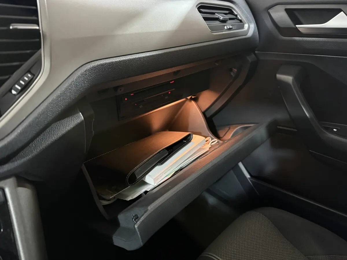 Gant de boîte à gants ouvert côté passager dans un Volkswagen T-Roc blanc, intérieur noir avec éclairage doux.