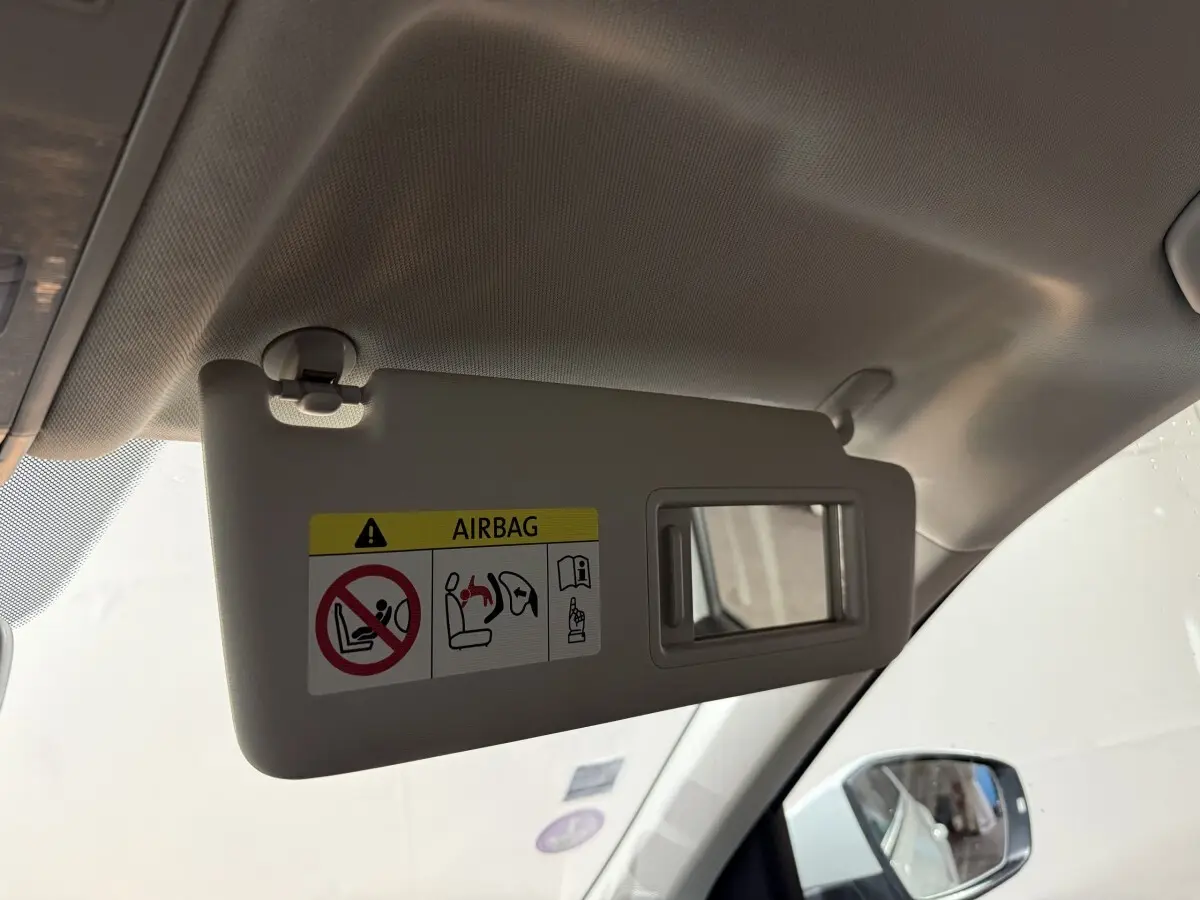 Pare-soleil côté conducteur beige avec miroir intégré et avertissement airbag dans un Volkswagen T-Roc blanc 2020.