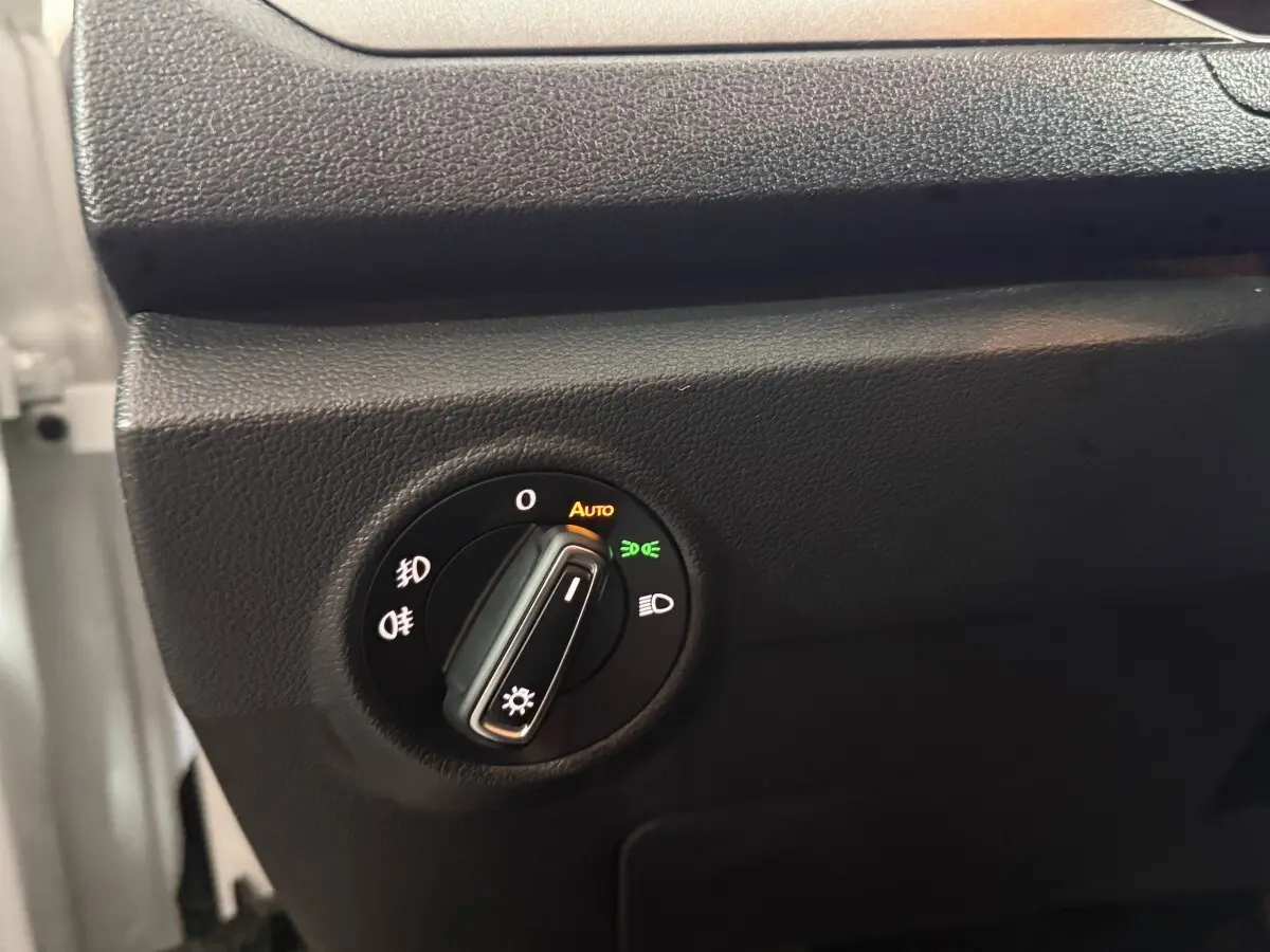 Gros plan sur la commande des phares du Volkswagen T-Roc blanc 2020, avec réglage automatique activé.