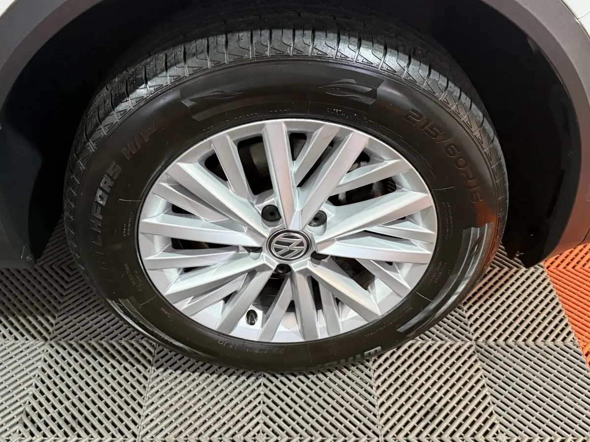 Gros plan sur la roue avant droite du Volkswagen T-Roc blanc, mettant en valeur la jante alliage à rayons fins.