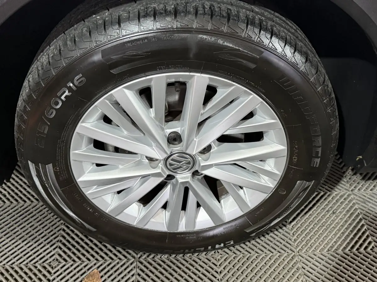 Gros plan sur la roue avant droite du Volkswagen T-Roc blanc avec jante alliage argentée et logo VW central.