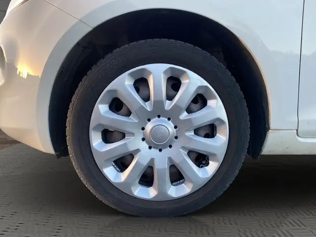 Gros plan sur la roue avant gauche d'une Ford Ka blanche de 2015, avec enjoliveur argenté à dix branches.