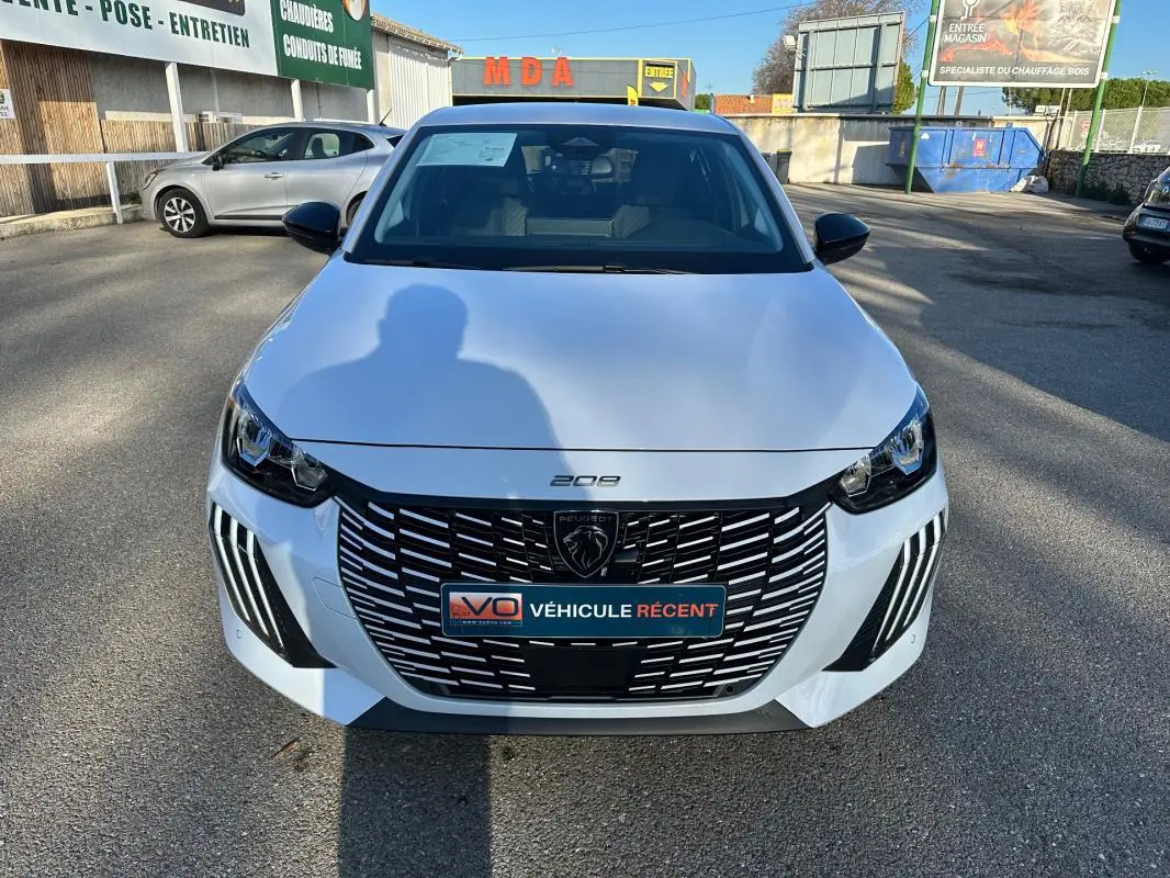 Vue avant d'une Peugeot 208 Hybrid 110 e-DCS6 Allure blanche avec calandre noire et feux LED distinctifs.