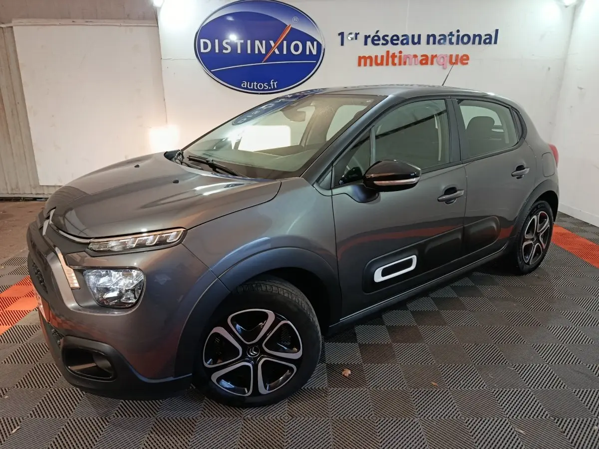 Citroën C3 gris foncé vue 3/4 avant droit, avec protections latérales noires et jantes stylisées.
