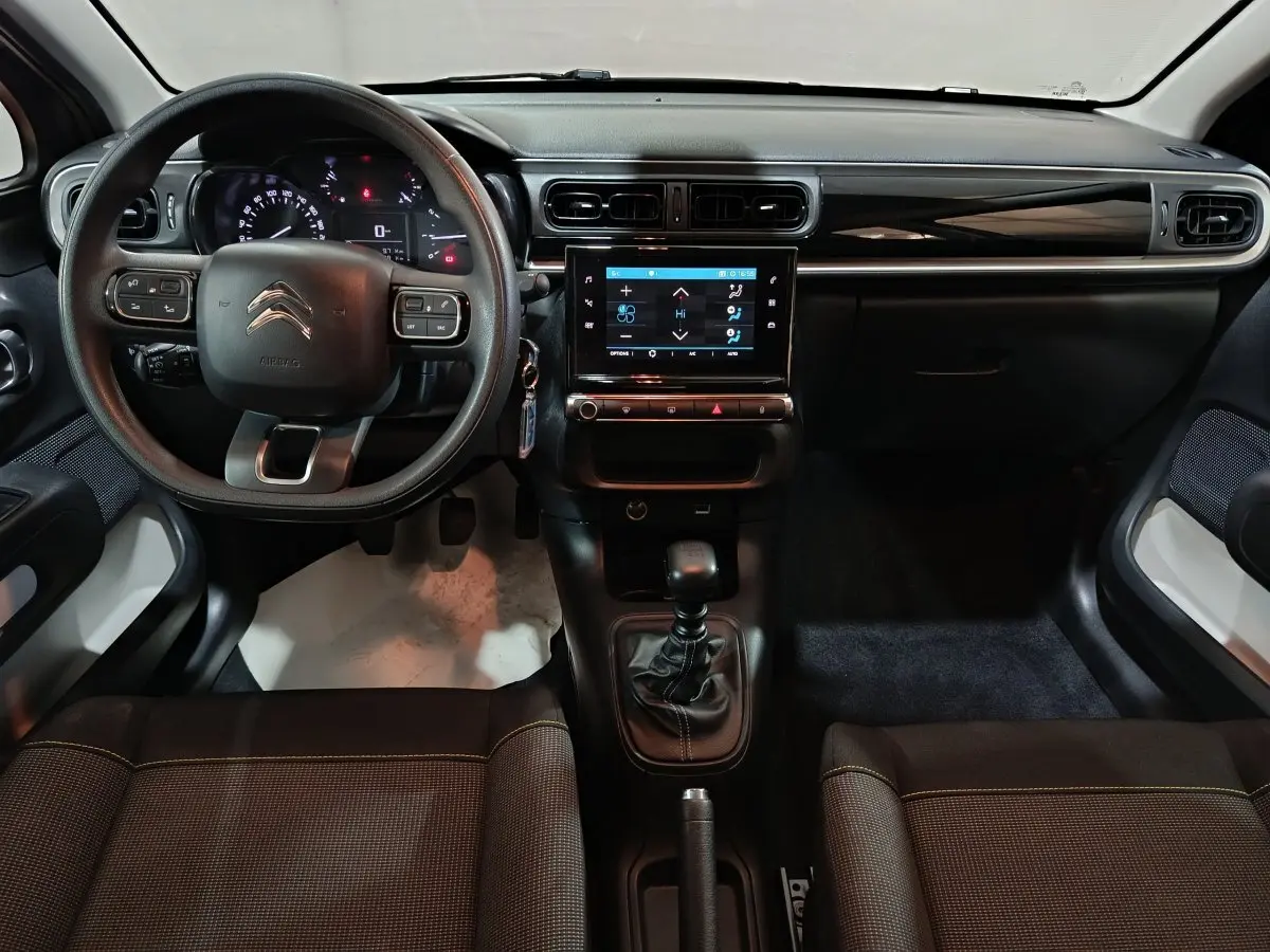 Vue intérieure avant du Citroën C3 gris foncé 2024, volant multifonctions, écran tactile central et boîte manuelle.