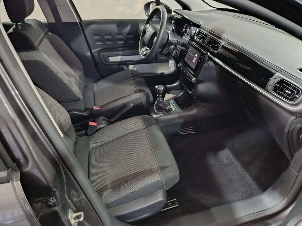 Vue intérieure côté conducteur de la Citroën C3 2024 gris foncé, avec tableau de bord tactile et volant multifonctions.
