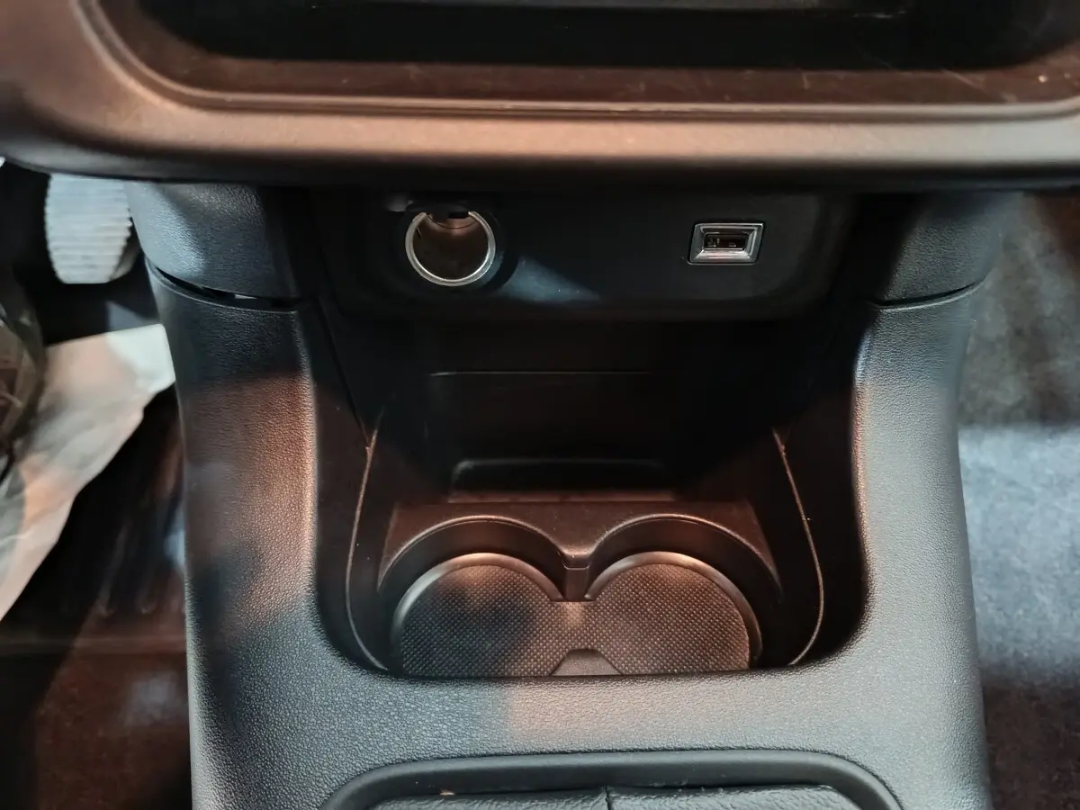 Gros plan de la console centrale noire de la Citroën C3 2024 avec prise 12V et port USB visible.