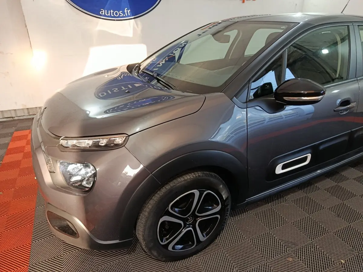 Vue 3/4 avant droit d'une Citroën C3 2024 gris foncé avec phares LED et protections latérales noires.