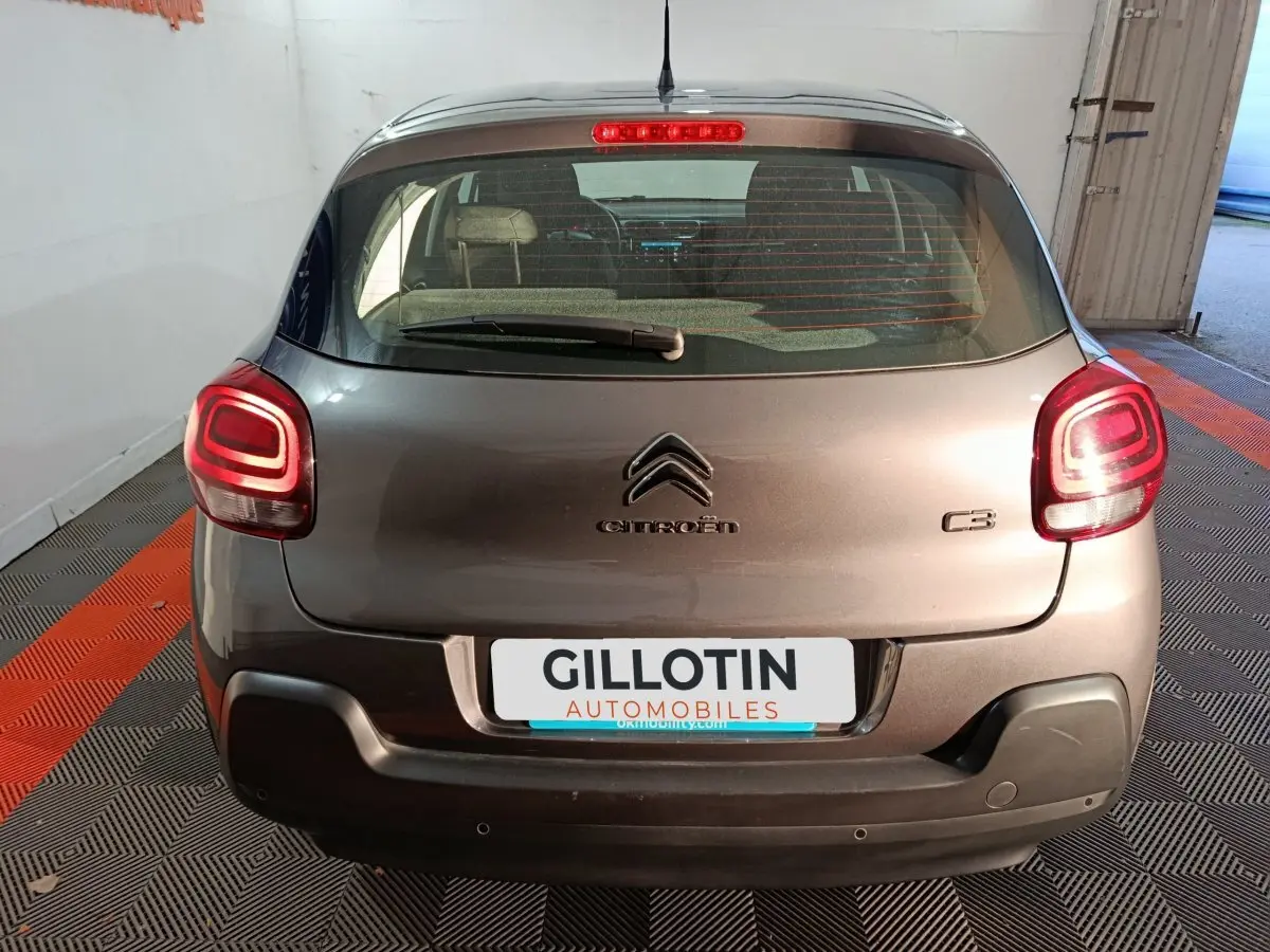 Vue arrière d'une Citroën C3 gris foncé 2024 avec feux arrière LED allumés dans un garage.