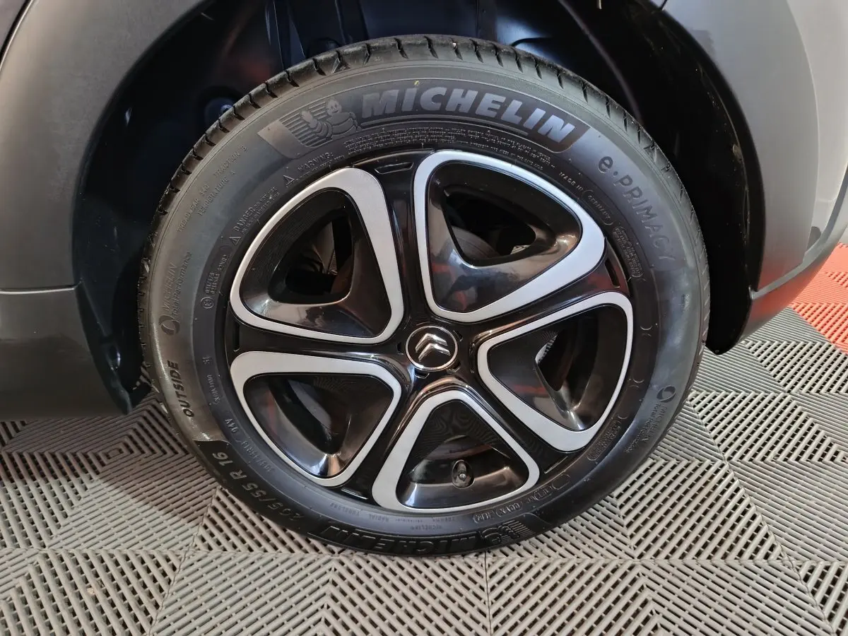 Gros plan sur la roue avant droite d'une Citroën C3 gris foncé, avec jante noire et argentée au design moderne.